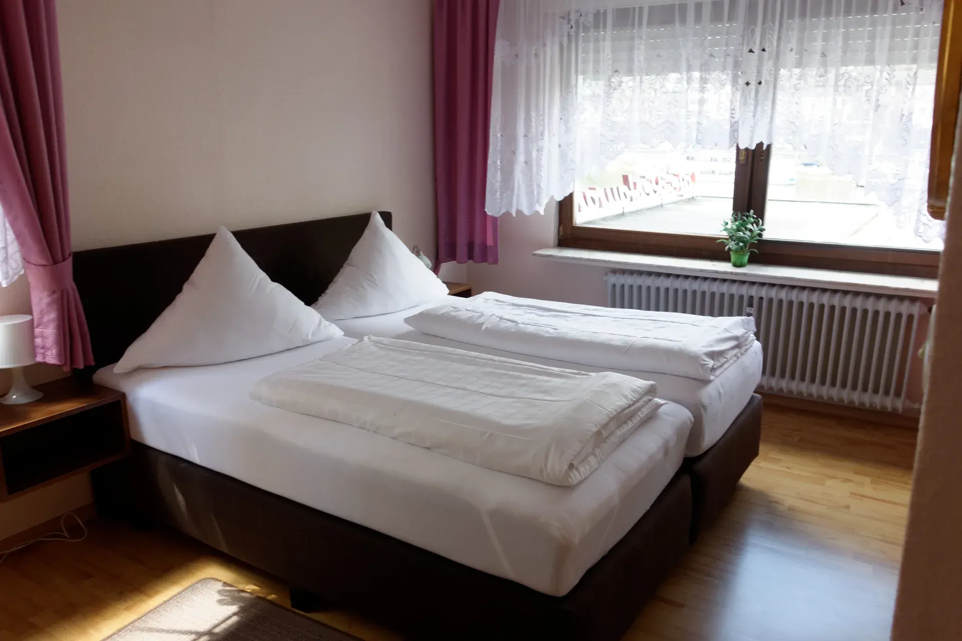 Eingerichtetes Doppelzimmer mit hellem Bett und Balkonzugang